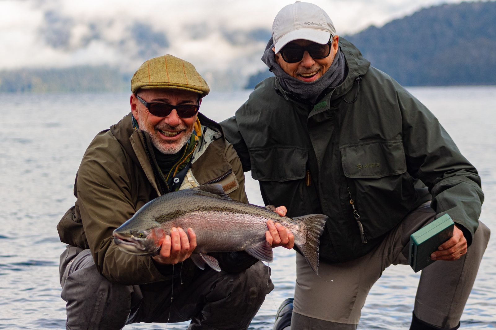 cliente con trucha arcoíris junto a guía de pesca en Patagonia